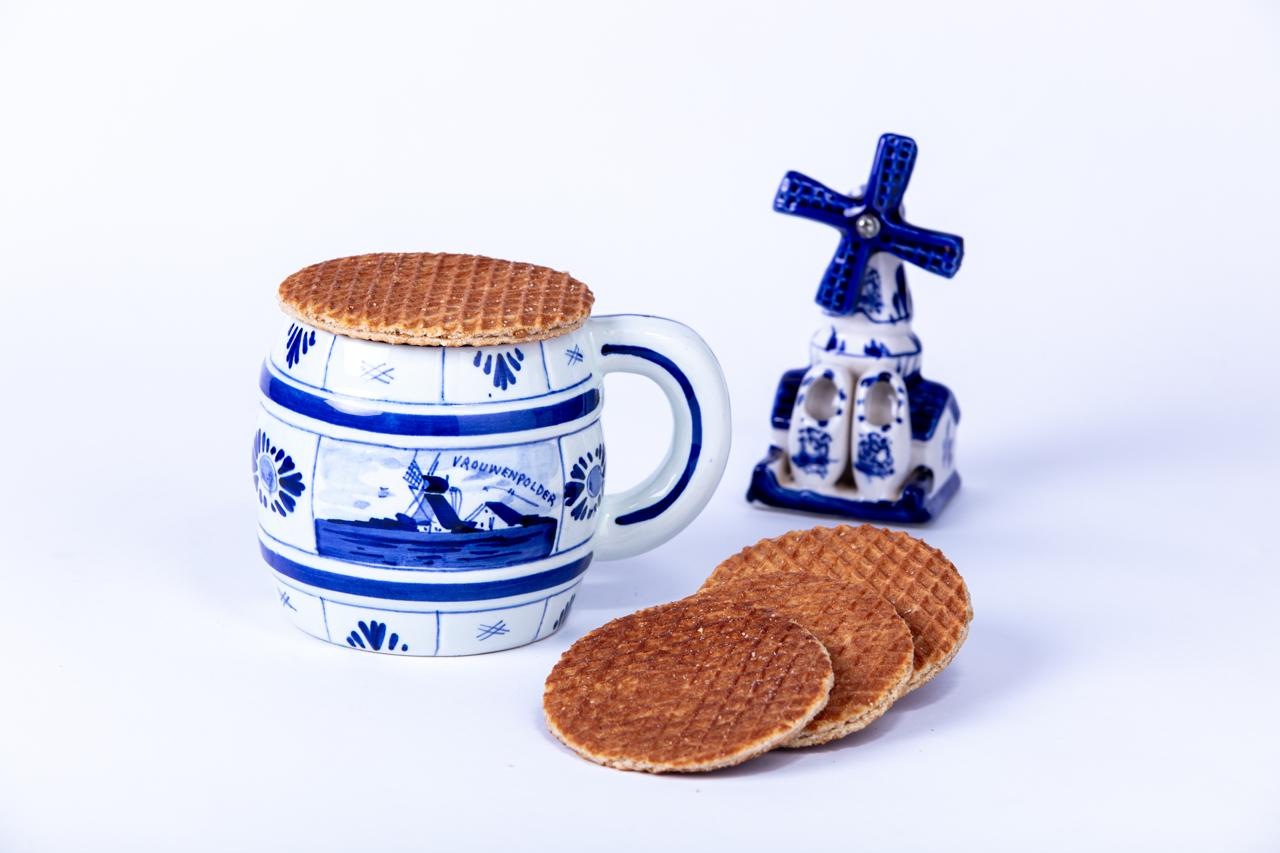 Stroopwafels deBakker com caneca azul e branca de inspiração Delft e um moinho holandês de porcelana