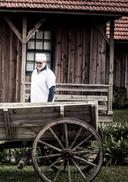 Padeiro com um carro de madeira diante de uma construção tradicional
